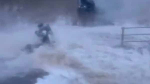 Moment woman is knocked off her mobility scooter by large wave